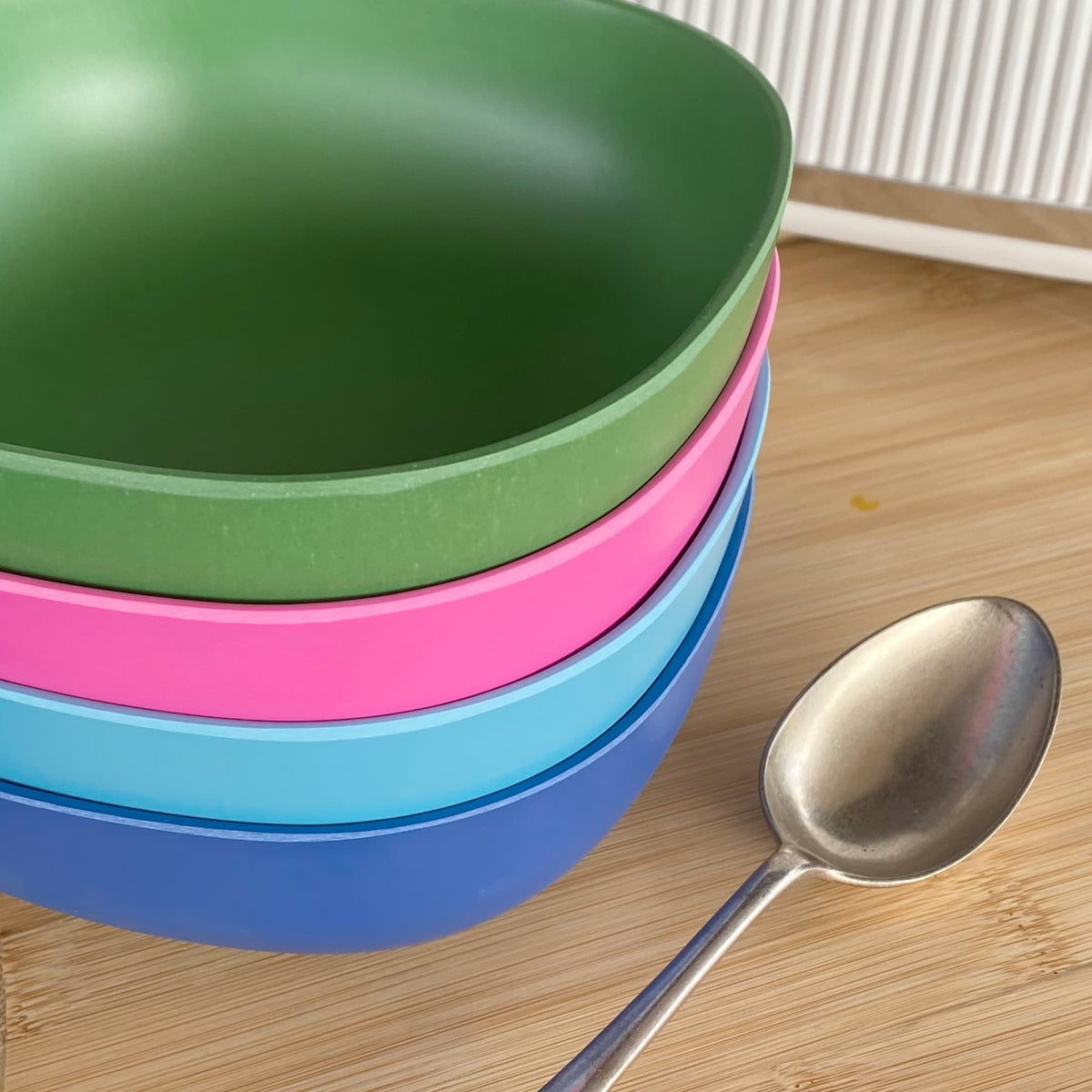4 piece bamboo cereal bowl set, coastal mix in classic green, vintage pink, pale blue and sea blue, on table with spoon