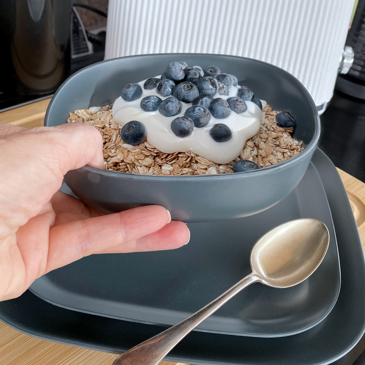 bamboo cereal bowl 15cm in midnight grey, destinations collection, held in hand and with breakfast