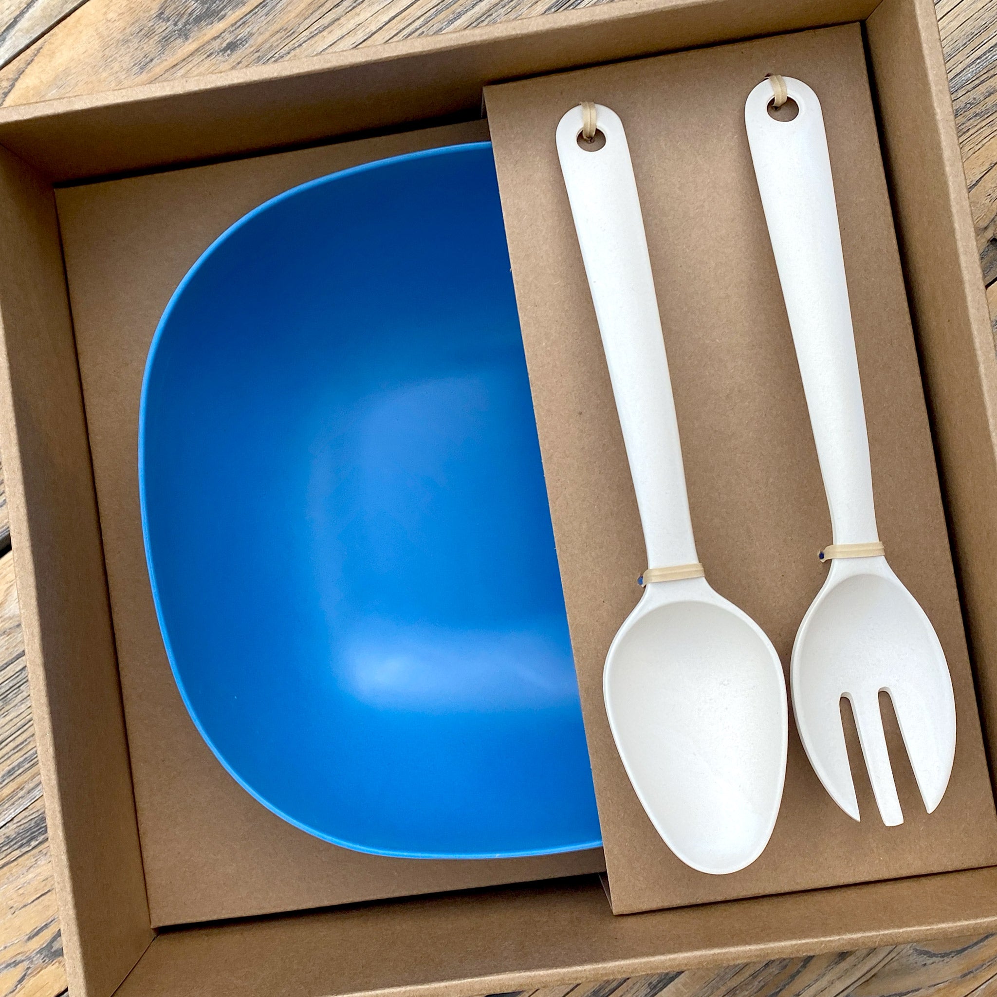 Van Go Bamboo Salad Bowl and Servers Set in cobalt blue with natural salad servers shown in brown gift box on timber table