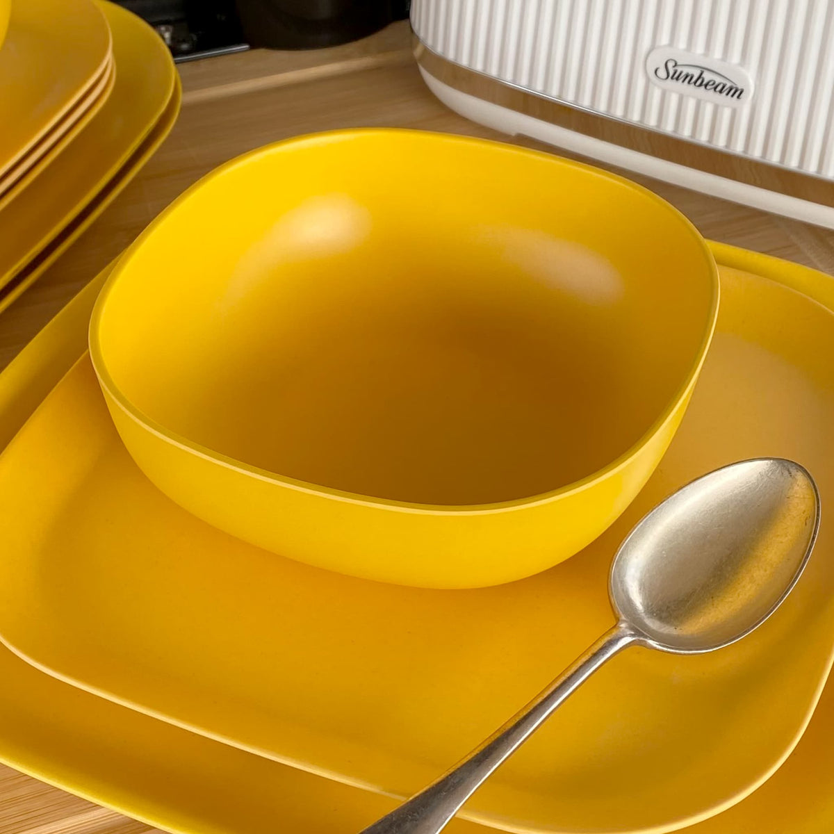 bamboo cereal bowl 15cm in sunshine yellow, on plate with spoon