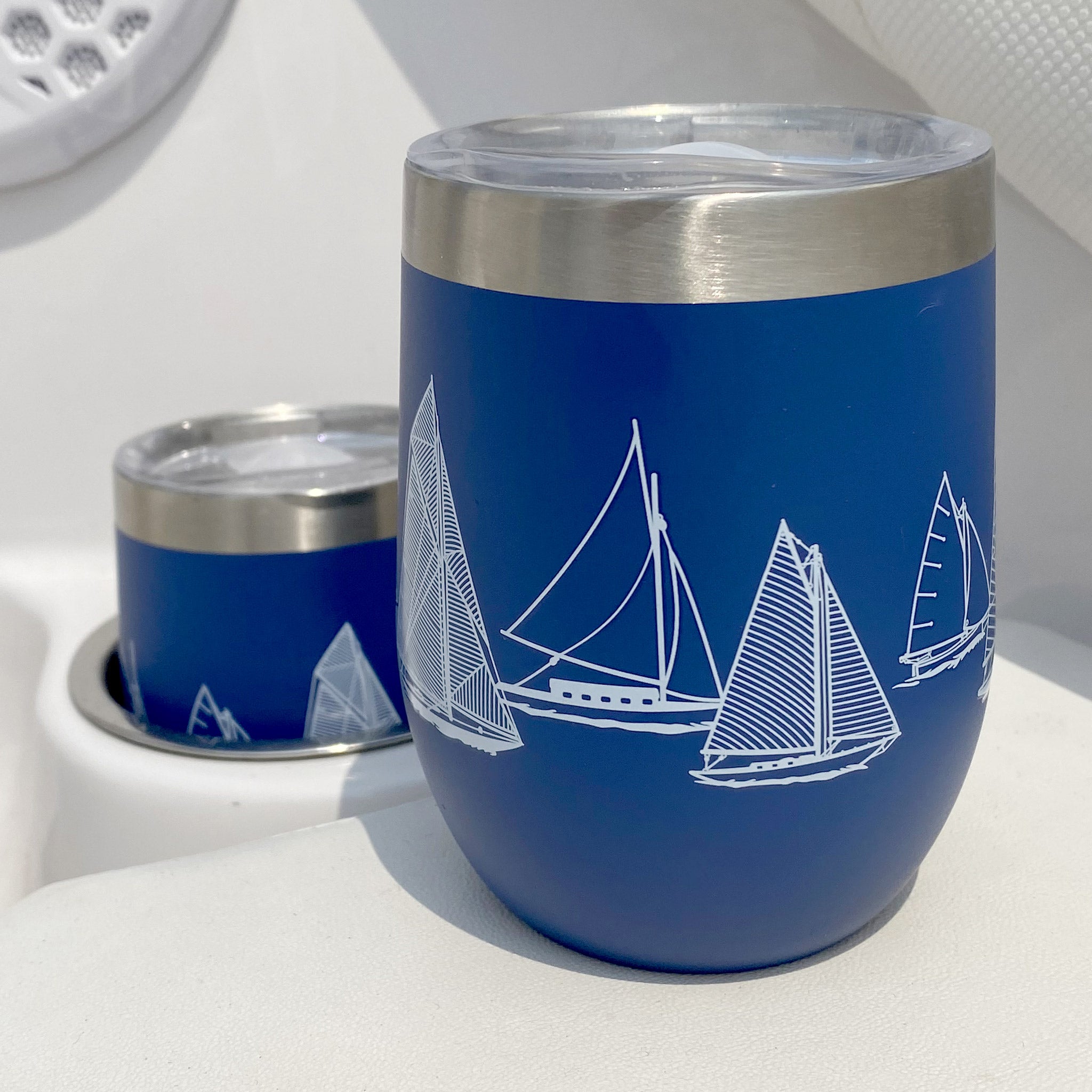 Two Blue Van Go Collections NautiGo Insulated Wine Cups with lids on a boat deck