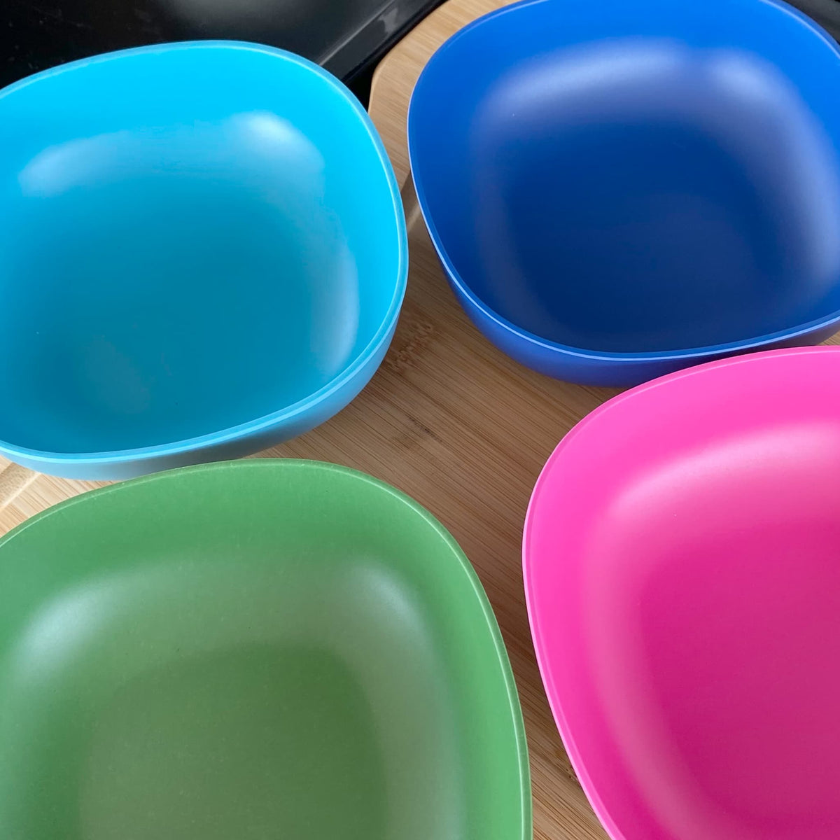 4 piece bamboo cereal bowl set, coastal mix in classic green, vintage pink, pale blue and sea blue, laid flat on table