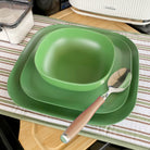 bamboo cereal bowl 15cm on 22cm and 26cm plates in classic green, iconic collection, close-up with spoon, on platemat