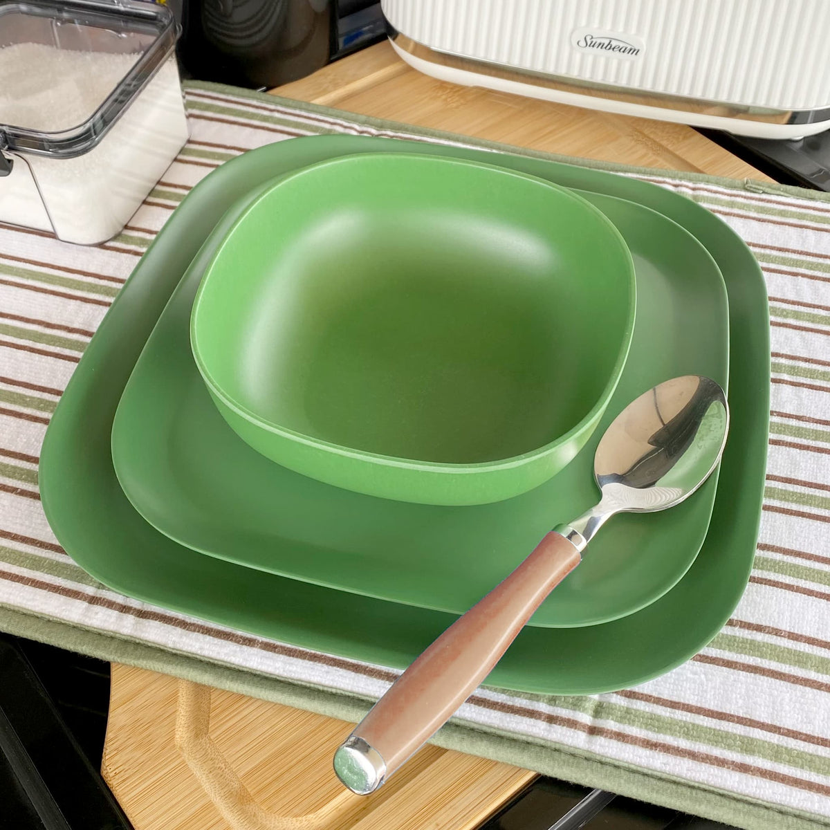 bamboo cereal bowl 15cm on 22cm and 26cm plates in classic green, iconic collection, close-up with spoon, on platemat