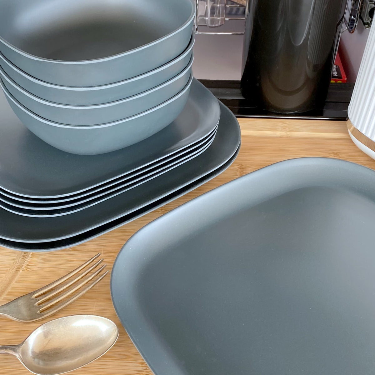 4 piece bamboo cereal bowl set, 22cm plate set and 26cm plate set in midnight grey, stacked and flat with cutlery