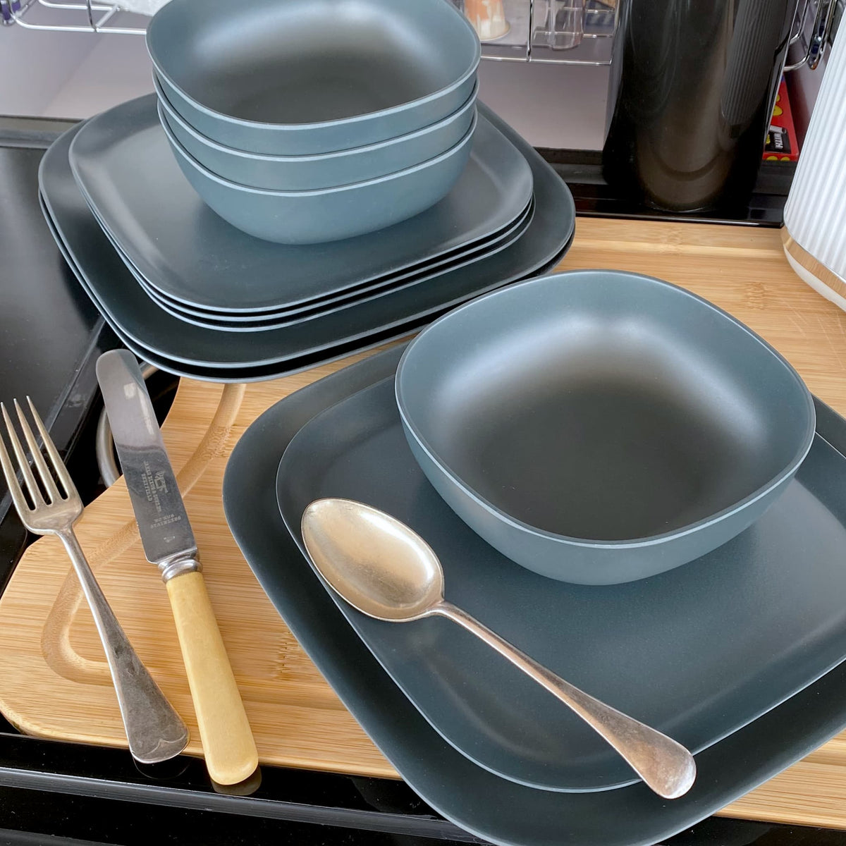 4 piece bamboo cereal bowl set, 22cm plate set and 26cm plate set in midnight grey, stacked and flat with cutlery
