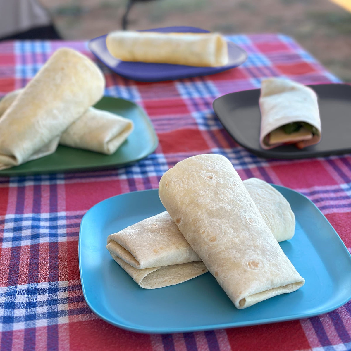 4 piece bamboo plate set 22cm, high country mix in classic green, midnight grey, pale blue and sea blue on a table with wraps