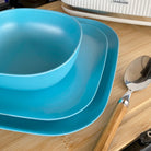 bamboo bowl, plate 22cm and 26cm in pale blue, cropped on table with spoon