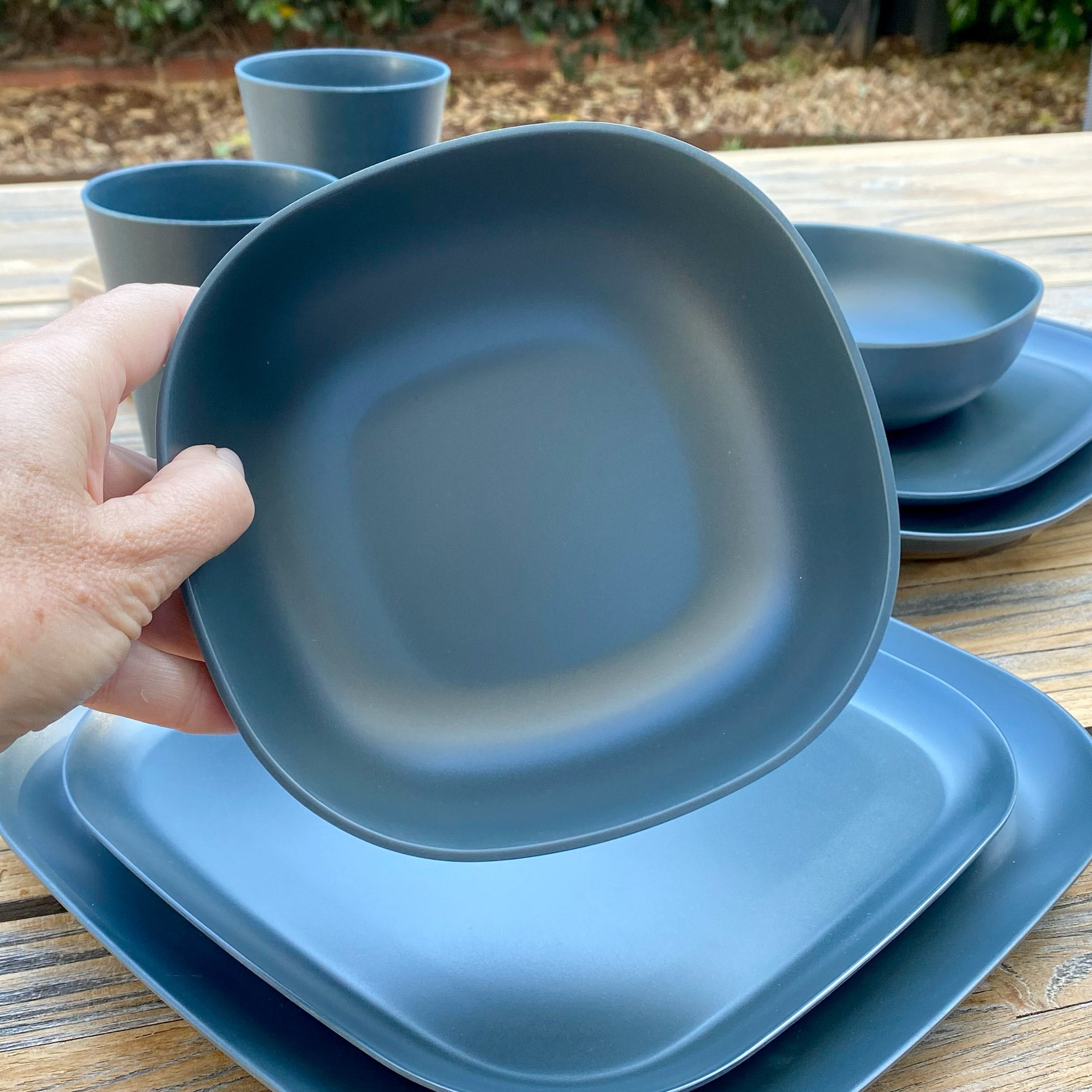 Van Go Caravan and camping 8 piece bamboo dinnerware set in classic midnight grey including camping plates, bowl and tumbler. Closeup of bowl on timber table