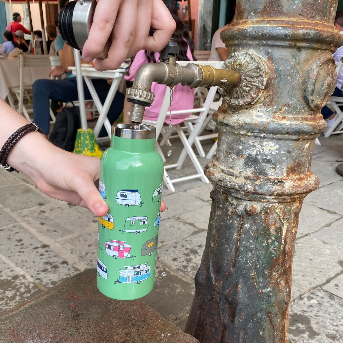 stainless steel water bottle with caravan print, iconic collection, filling at italian water fountain