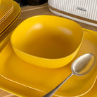 bamboo cereal bowl 15cm in sunshine yellow, on plate with spoon