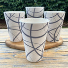 Four bamboo tumblers with geometric circles patterns on a wooden surface