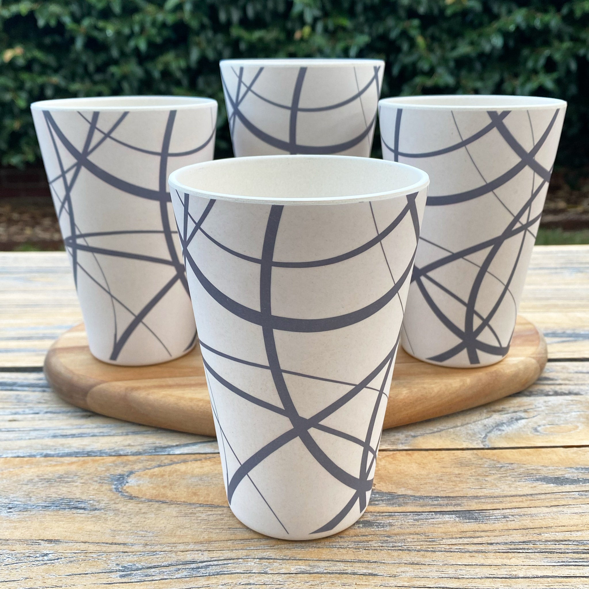Four bamboo tumblers with geometric circles patterns on a wooden surface